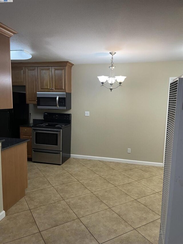 kitchen with light tile patterned flooring, appliances with stainless steel finishes, hanging light fixtures, and a notable chandelier