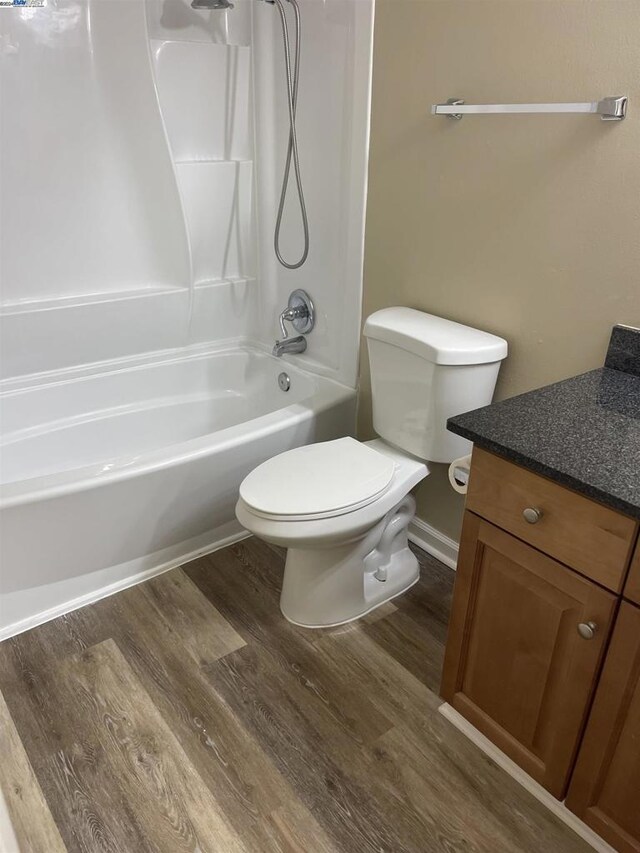 full bathroom featuring hardwood / wood-style flooring, toilet, vanity, and shower / washtub combination