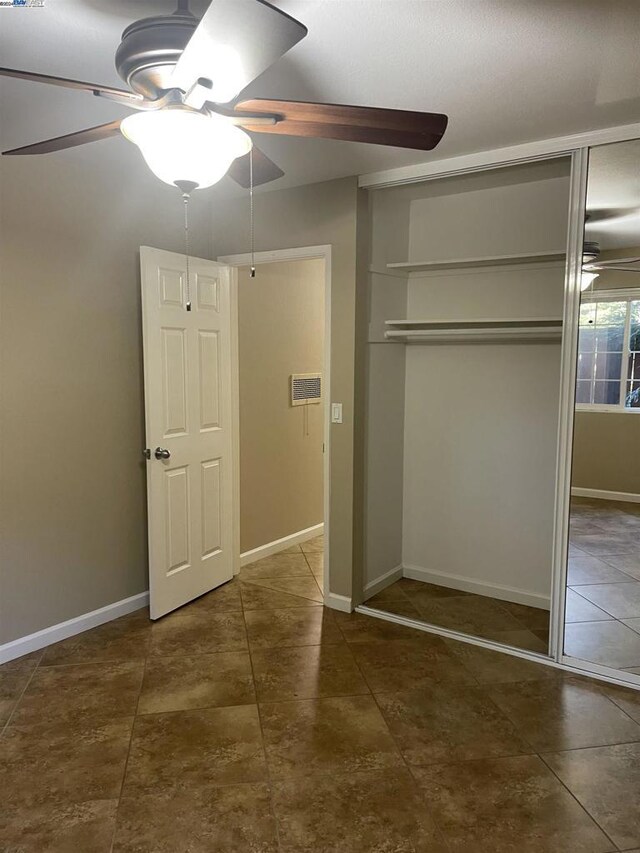 unfurnished bedroom with ceiling fan and a closet