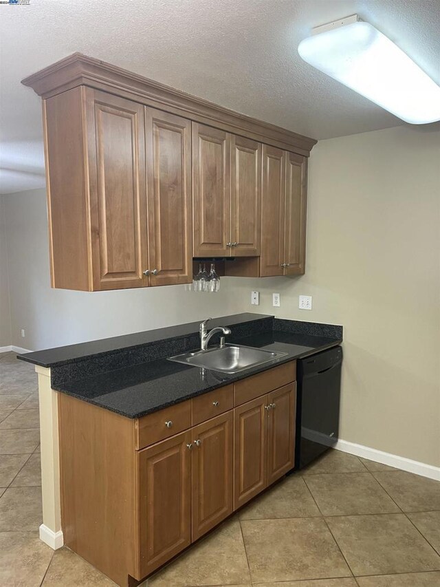 kitchen with light tile patterned floors, dishwasher, sink, and a textured ceiling