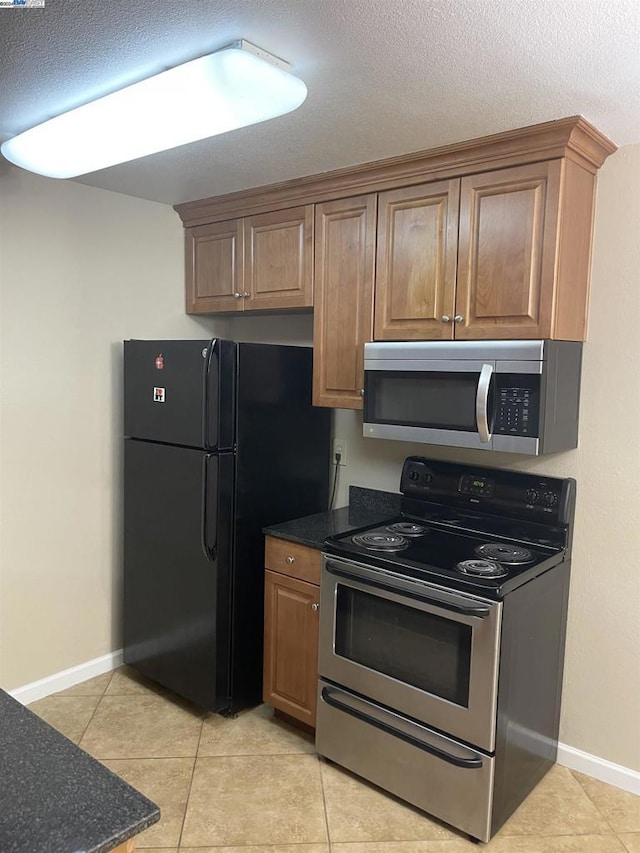 kitchen featuring a textured ceiling, light tile patterned floors, and stainless steel appliances