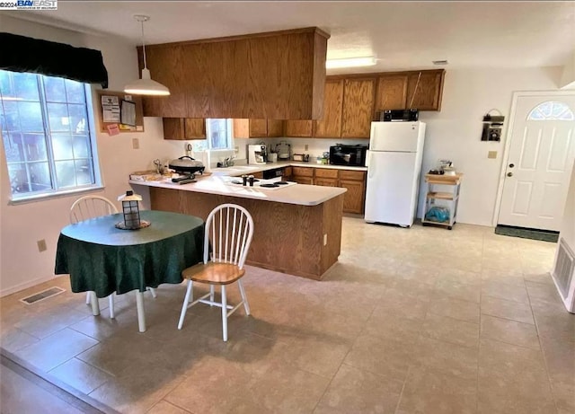 kitchen featuring hanging light fixtures, kitchen peninsula, white appliances, and plenty of natural light