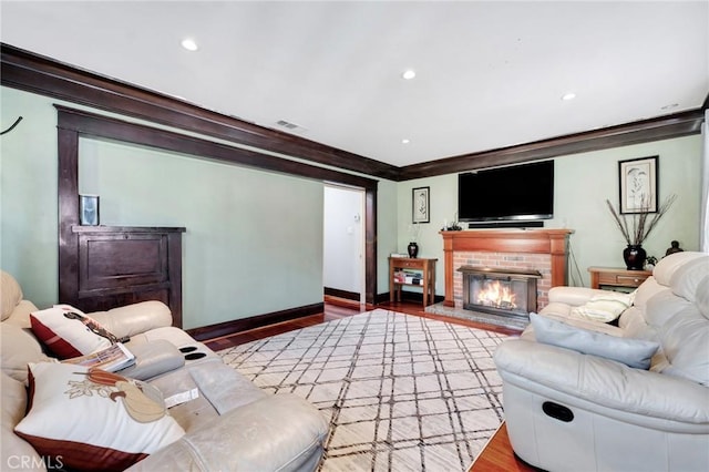 living room featuring a brick fireplace, crown molding, and wood-type flooring