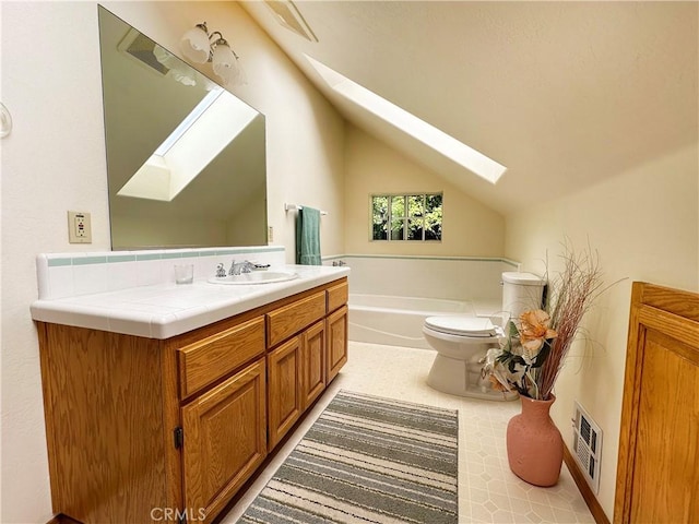 full bath with vaulted ceiling with skylight, a bath, visible vents, vanity, and toilet