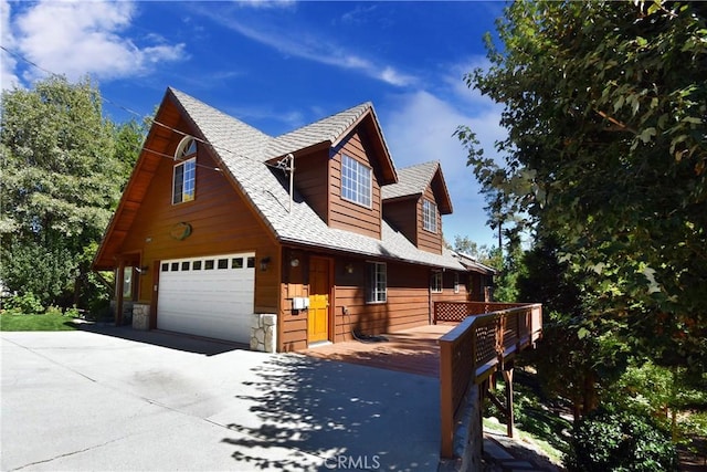 view of front facade with driveway, a shingled roof, stone siding, and a garage