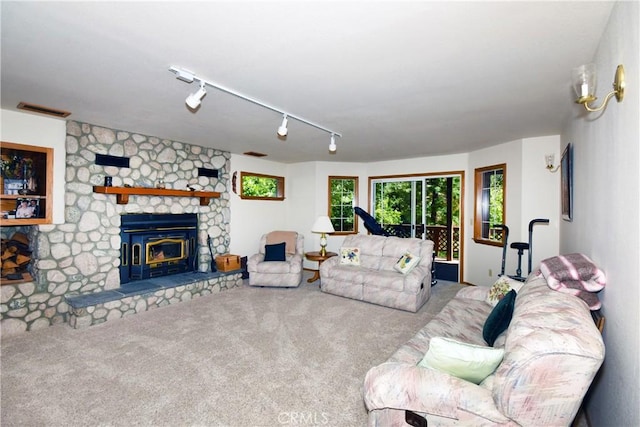 carpeted living room featuring track lighting and a stone fireplace