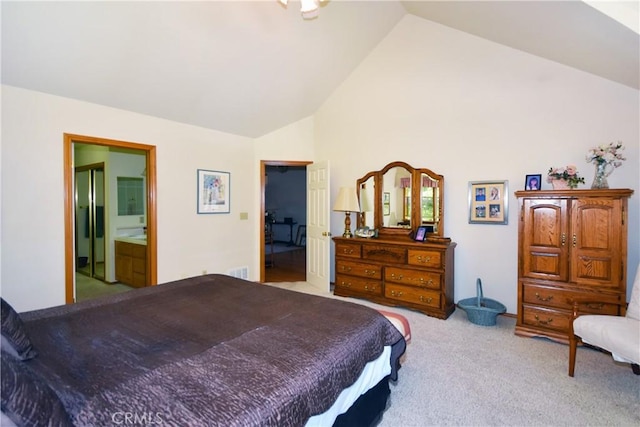 bedroom featuring light carpet, high vaulted ceiling, and ensuite bath