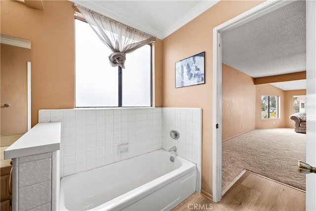 bathroom with vanity, a bath, hardwood / wood-style flooring, ornamental molding, and a textured ceiling