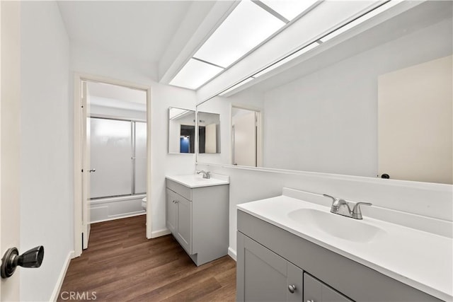 full bathroom featuring vanity, hardwood / wood-style flooring, toilet, and enclosed tub / shower combo