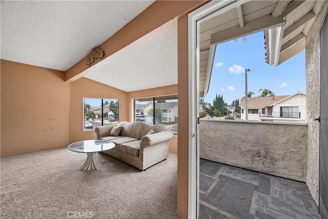 carpeted living room featuring lofted ceiling with beams and a textured ceiling