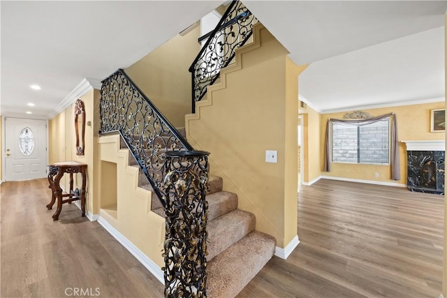 staircase featuring a fireplace, hardwood / wood-style floors, and ornamental molding