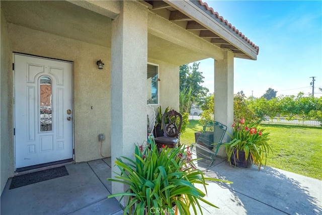 view of exterior entry with a patio area and a yard