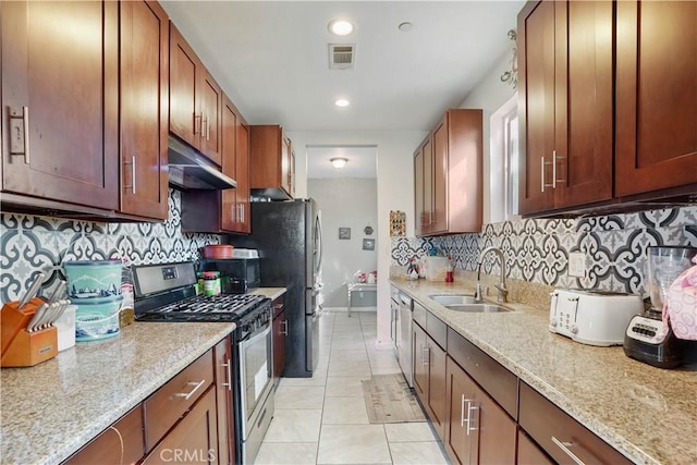 kitchen with light tile patterned floors, stainless steel appliances, backsplash, light stone countertops, and sink