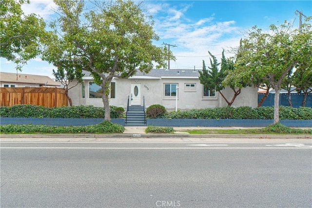 view of front of house with fence and stucco siding