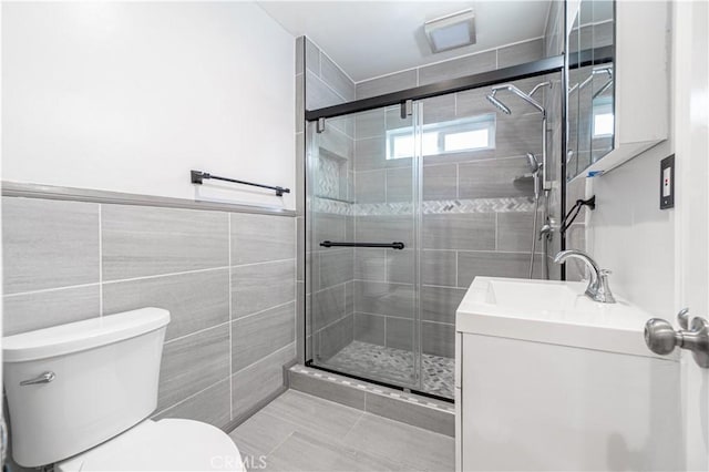 full bathroom featuring toilet, vanity, a shower stall, and tile walls