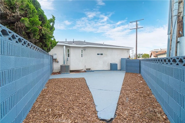 rear view of house featuring a fenced backyard, central AC unit, a patio, and stucco siding