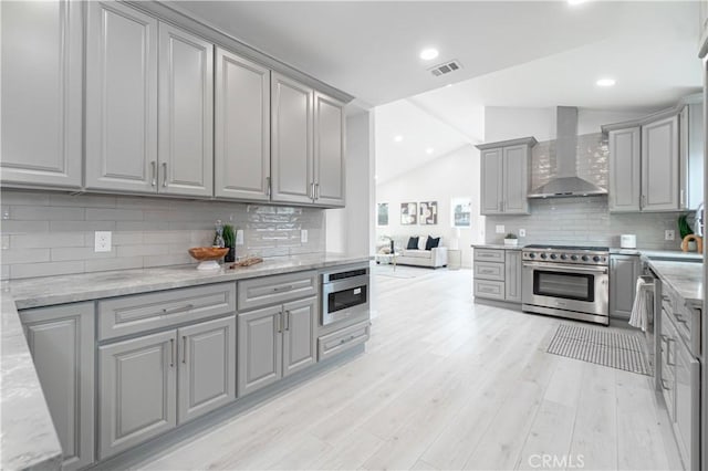 kitchen featuring wall chimney exhaust hood, high end stainless steel range oven, and gray cabinetry