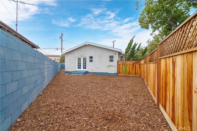 back of property with entry steps, french doors, a fenced backyard, and stucco siding