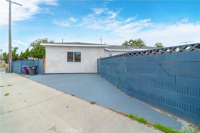 exterior space featuring a patio area, fence, and stucco siding