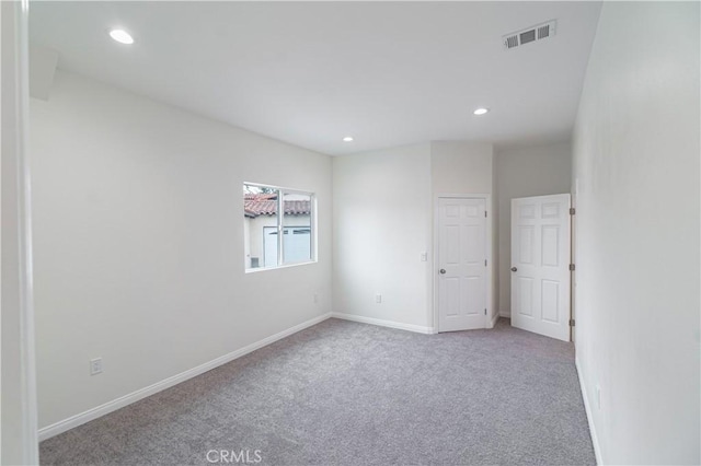 carpeted spare room featuring recessed lighting, visible vents, and baseboards