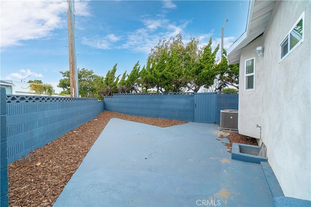 view of yard featuring a gate, a fenced backyard, a patio, and central AC unit