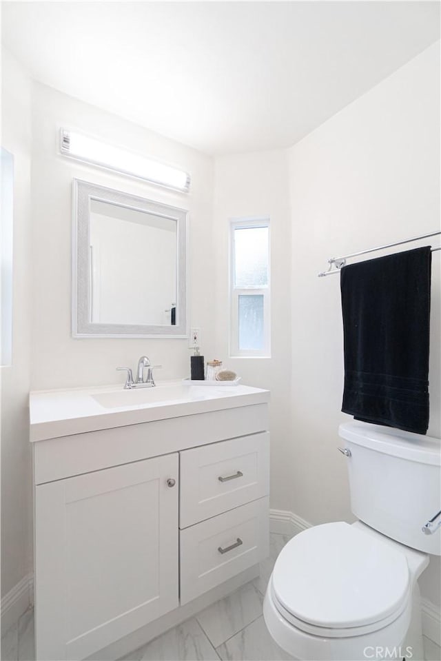 bathroom with toilet, marble finish floor, baseboards, and vanity