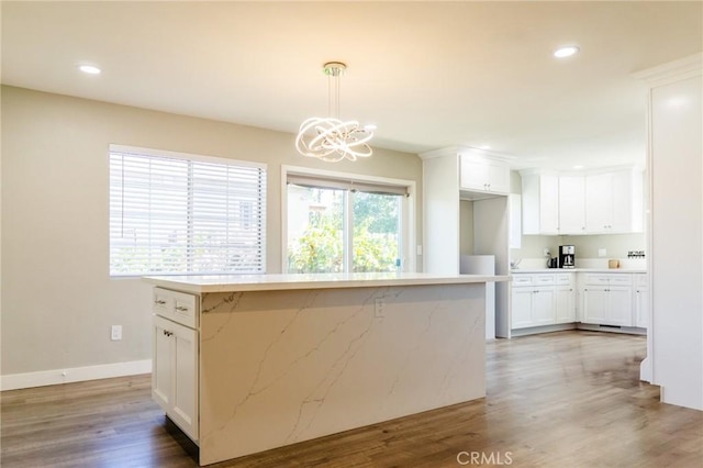 kitchen featuring decorative light fixtures, white cabinetry, hardwood / wood-style flooring, and a kitchen island