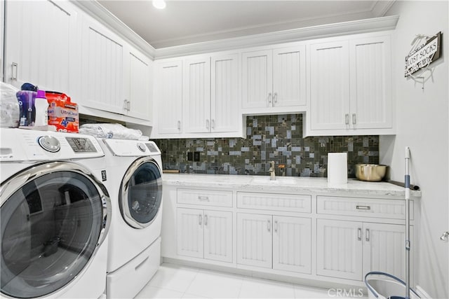 clothes washing area with cabinets, light tile patterned floors, washer and dryer, ornamental molding, and sink