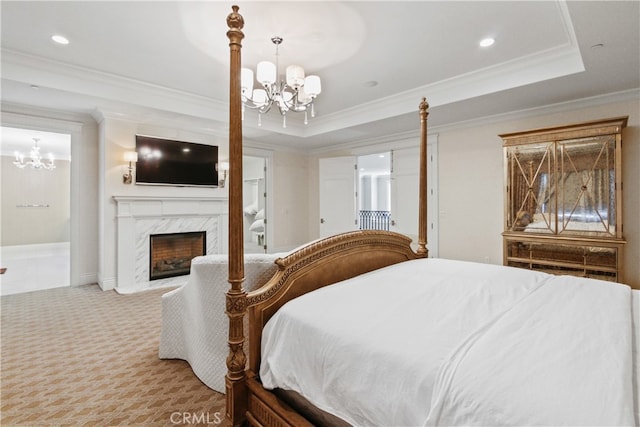 carpeted bedroom featuring connected bathroom, a high end fireplace, ornamental molding, an inviting chandelier, and a raised ceiling