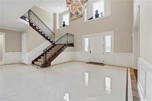 foyer entrance featuring a chandelier, ornamental molding, a high ceiling, and tile patterned flooring