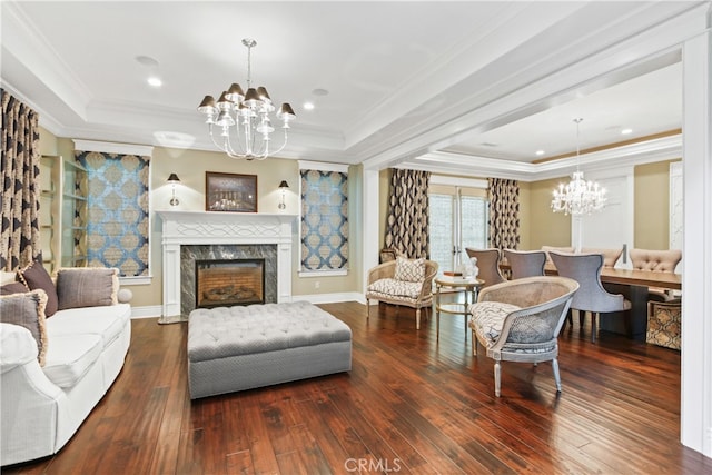 living room with an inviting chandelier, dark wood-type flooring, a fireplace, and a raised ceiling