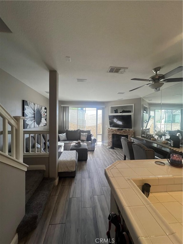 living room with a textured ceiling, ceiling fan, and dark wood-type flooring