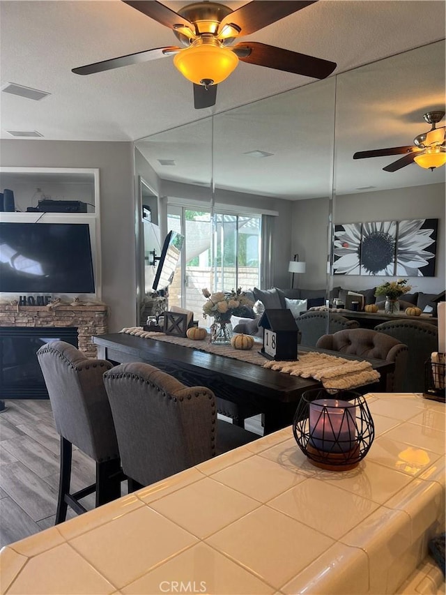 dining space with a stone fireplace, wood-type flooring, and a textured ceiling