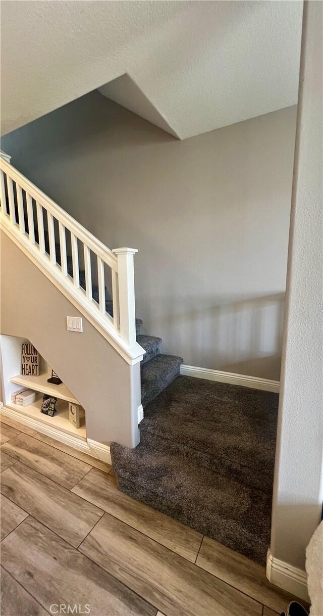 stairs with hardwood / wood-style flooring and a textured ceiling