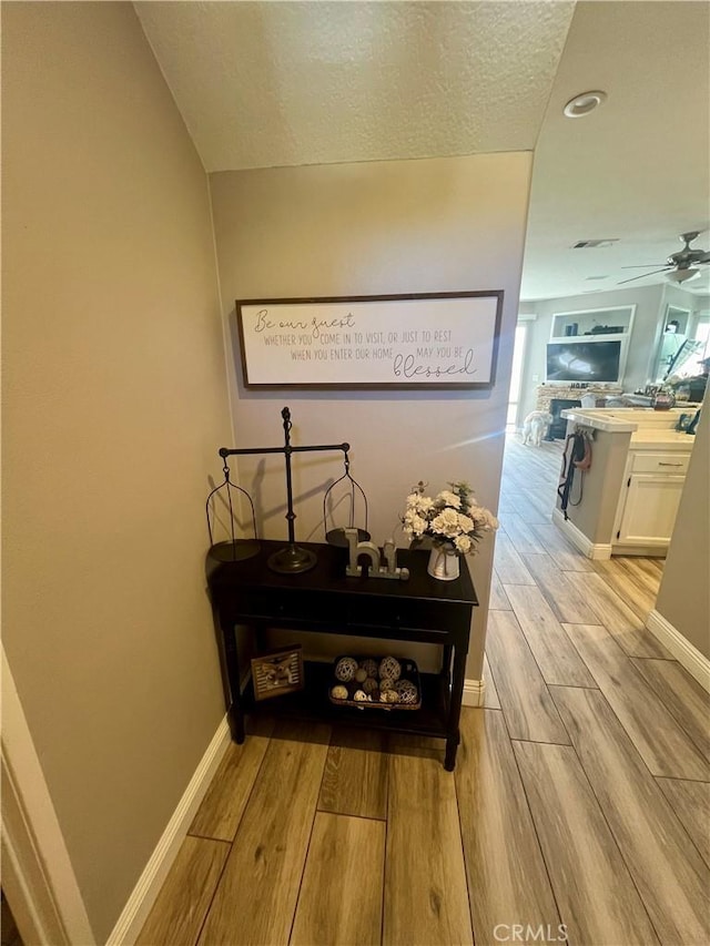 hall with a textured ceiling and light hardwood / wood-style flooring