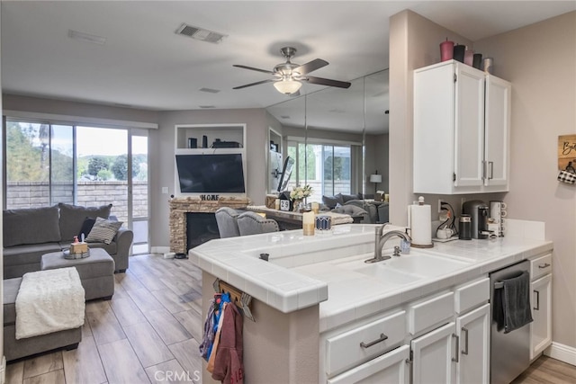 kitchen with white cabinets, a sink, dishwasher, open floor plan, and visible vents