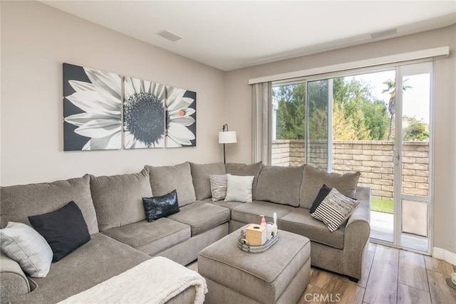 living area featuring baseboards, light wood finished floors, and visible vents