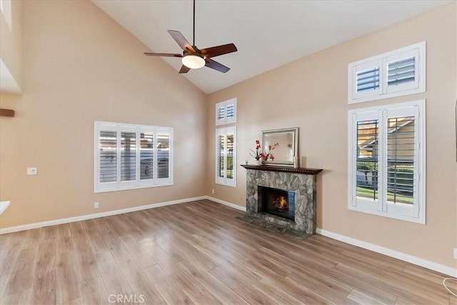 unfurnished living room featuring a fireplace, light hardwood / wood-style flooring, high vaulted ceiling, and a healthy amount of sunlight