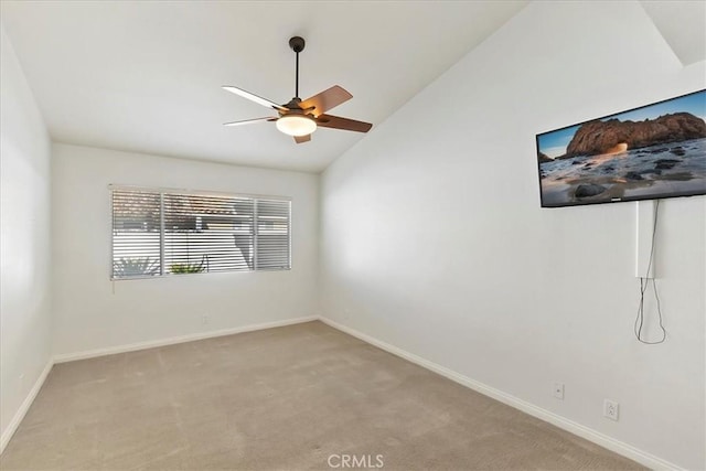 spare room with ceiling fan, light carpet, and vaulted ceiling