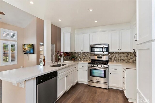 kitchen featuring kitchen peninsula, stainless steel appliances, white cabinets, and sink