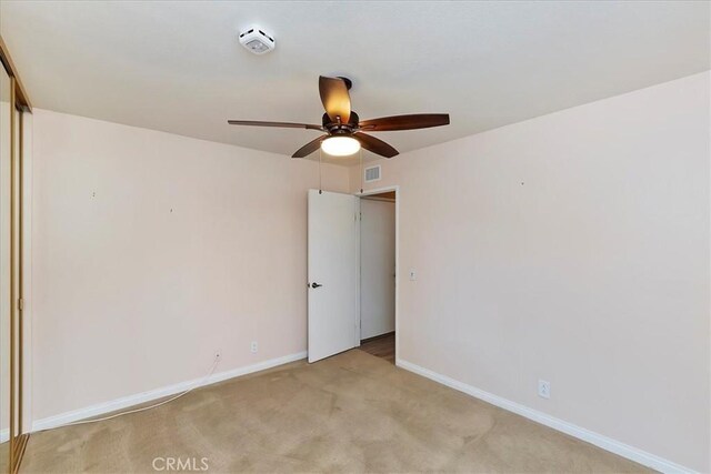 carpeted spare room featuring ceiling fan