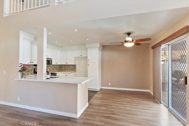 kitchen featuring kitchen peninsula, backsplash, white cabinets, and light hardwood / wood-style flooring