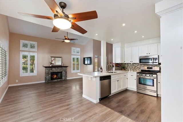 kitchen with kitchen peninsula, white cabinets, stainless steel appliances, and light hardwood / wood-style floors