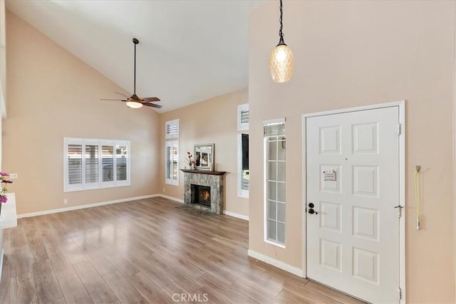 foyer entrance with a premium fireplace, ceiling fan, high vaulted ceiling, and wood-type flooring