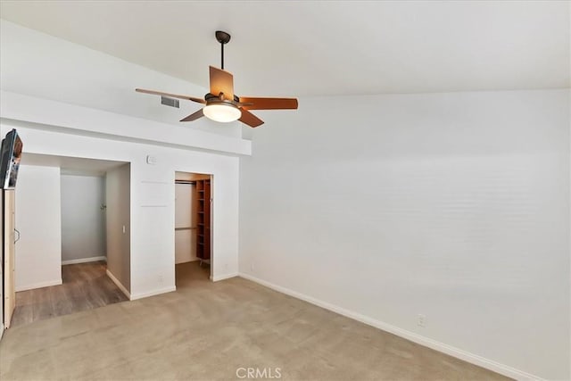 unfurnished bedroom featuring ceiling fan, vaulted ceiling, light carpet, and a closet