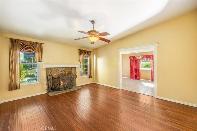 unfurnished living room featuring a stone fireplace, ceiling fan, and hardwood / wood-style floors