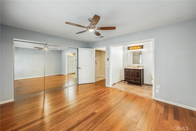 unfurnished bedroom featuring ceiling fan, light wood-type flooring, connected bathroom, and a closet