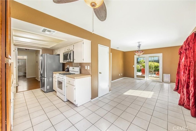 kitchen featuring ceiling fan, white cabinetry, stainless steel appliances, and light tile patterned floors