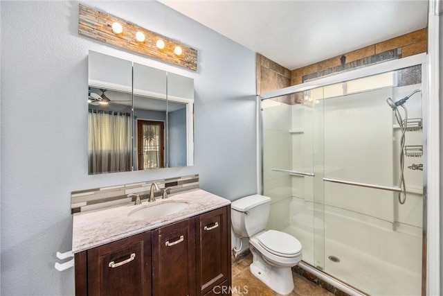 bathroom with ceiling fan, a shower with door, vanity, and toilet