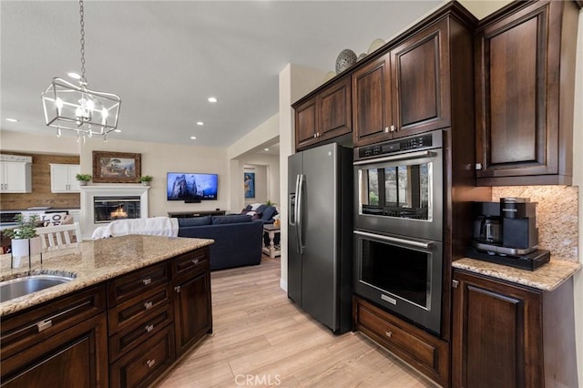 kitchen featuring decorative backsplash, appliances with stainless steel finishes, decorative light fixtures, an inviting chandelier, and light hardwood / wood-style floors